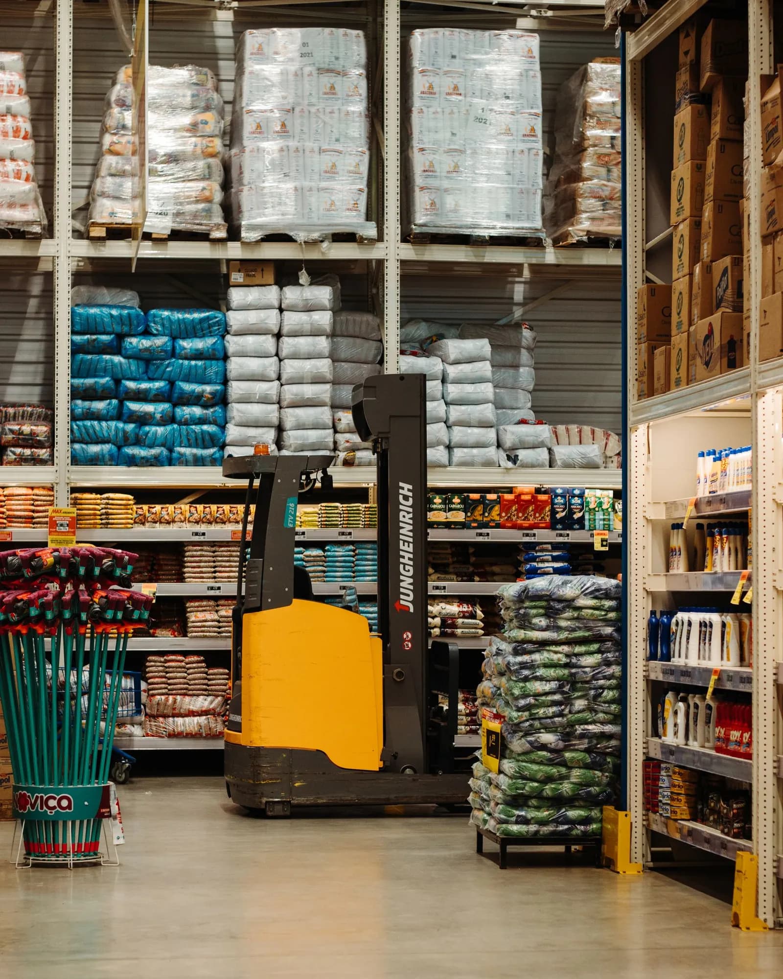 Warehouse racks with stacked goods and a lift in the access aisle