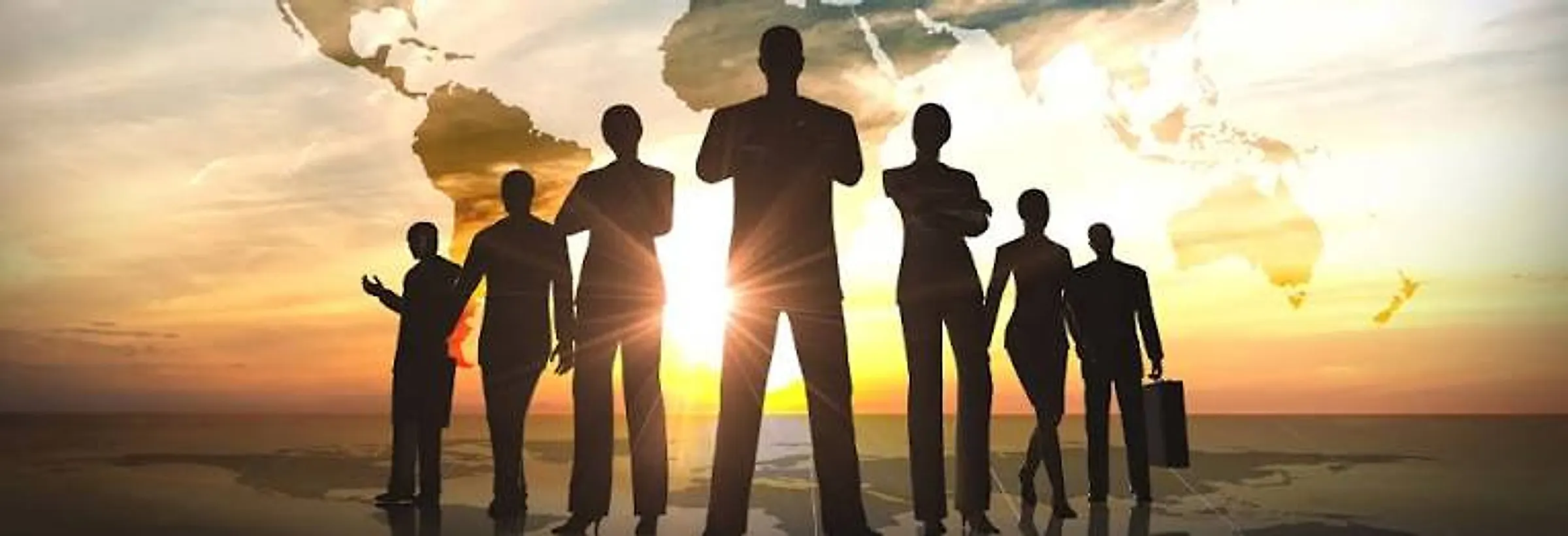 Silhouettes of a team standing together against a sunrise